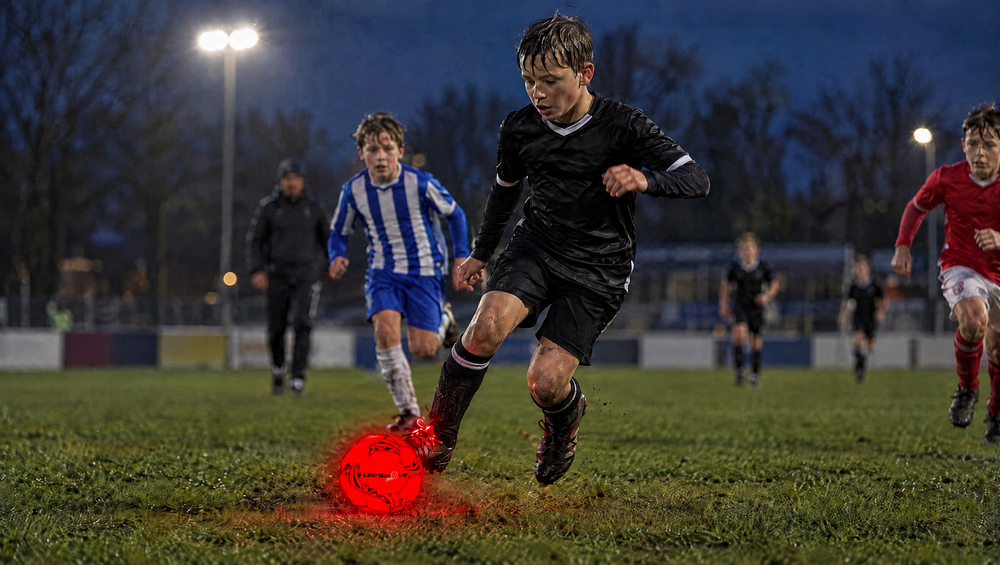 Jeugdwedstrijd onder lichtmasten met de lichtgevende LED voetbal